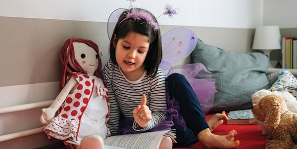 Girl disguised reading a book to her doll